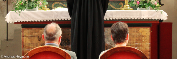 Paar sitzend vor Altar mit Pfarrerin